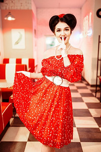 漂亮的美女化妆，红色连衣裙与白色圆点，复古风格。复古咖啡厅内部与棋盘地板