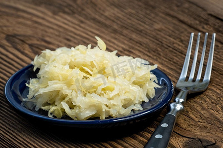 自制腌酸菜在一个碗与叉子在木板上