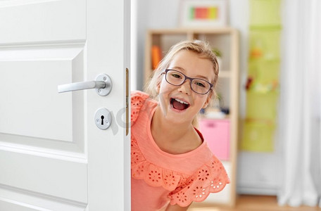 童年，乐趣和人的概念—快乐的微笑美丽的女孩在门后的眼镜在家里。快乐的微笑美丽的女孩在门后面在家里