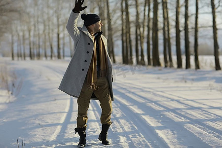 穿着大衣/冬装的时尚男士，在冬日风景的映衬下行走，雪天，暖和的衣服