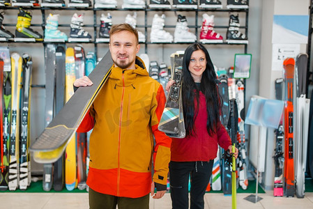 体育体育用品摄影照片_夫妇手里拿着滑雪板，在体育用品店购物。冬季极端的生活方式，活跃的休闲商店，客户购买滑雪设备