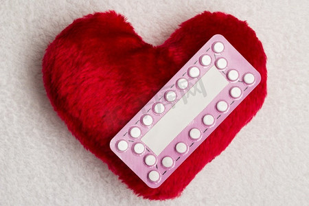 药物、避孕、爱情和节育。红色心形小枕头上的口服避孕药