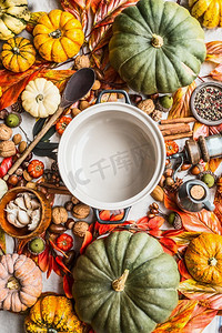 空的焦化锅与木勺在桌子上与许多各种各样的五颜六色的南瓜和其他秋天的配料：坚果和香料。俯视图。拷贝空间