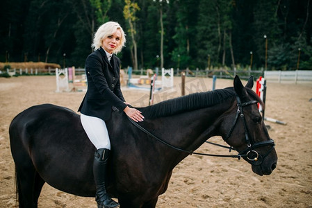 女子骑马摄影照片_马术运动，女子骑马姿势。棕色种马，悠闲地和动物在一起，骑在马上。马术运动，女子骑马姿势