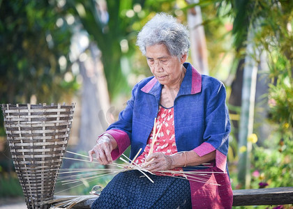 竹人摄影照片_亚洲生活在家里工作的老妇人/祖母严重生活在生活的农村人在泰国编织竹篮工艺品