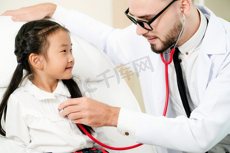 年轻的男医生在医院的办公室里给小孩子做检查。这孩子很开心，也不怕医生。医疗儿童保健理念。