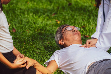 一位老人在公园里有胸痛或心脏病发作。老年人老年人保健概念医生帮助晕倒在地上的老年人。