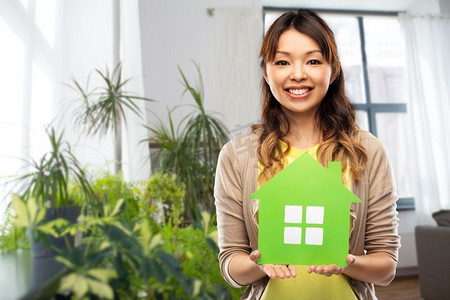 生态，环境和抵押概念—愉快的亚洲年轻妇女有绿色房子在家背景快乐的亚洲女人与绿色的房子在家里