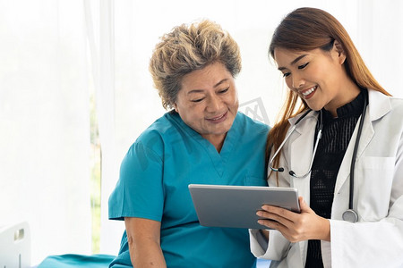 医生患者平板电脑摄影照片_亚洲人信心医生使用数字平板电脑表达健康关注与老老年妇女病人坐在床上