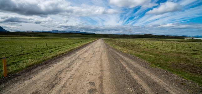 空旷的砾石土路穿过乡村景观和草地。四轮驱动汽车的自然越野旅行。