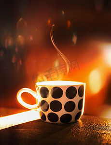 波尔卡摄影照片_波尔卡点杯与蒸汽表在橙色日落光与散景。室内热饮料