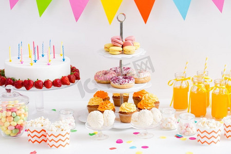 派对banner摄影照片_派对和节日概念—生日蛋糕，蜡烛和草莓，饮料和食物上桌。生日派对上的食物和饮料