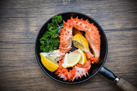 蟹菜摄影照片_煮蟹爪在平底锅与阿拉斯加国王蟹海鲜在餐桌背景/红蟹北海道