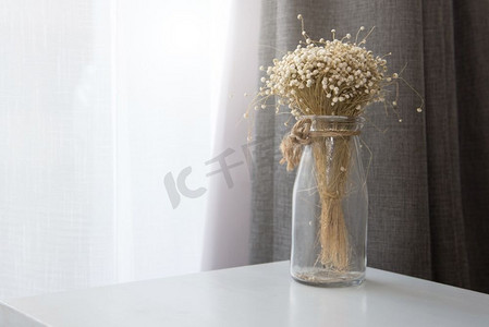 客厅的透明玻璃花瓶里的干花。装饰和室内概念。