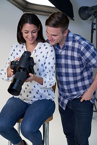 男性和女性摄影师在工作室的照片拍摄与相机和照明设备    