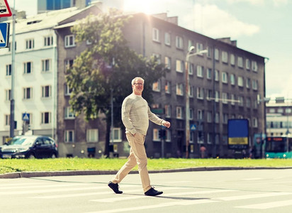 康乐与人文概念—长者漫步在夏日城市人行横道。一名老人在城市人行横道上行走