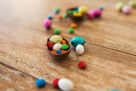 复活节，糖果和糖果概念—关闭巧克力蛋和糖果滴在木桌上。巧克力蛋和糖果滴在木桌上