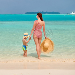 三岁的小男孩和妈妈一起在海滩上。暑假在马尔代夫度假。