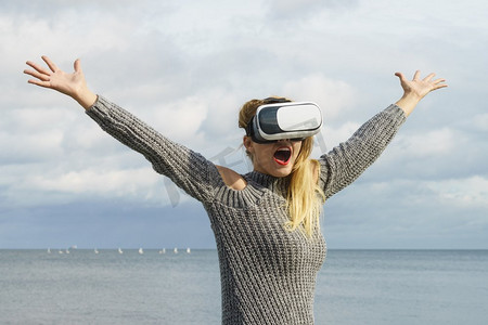 一名年轻女子在外面测试VR眼镜。女性在春天的天气里戴着虚拟现实耳机。戴着VR的女人在外面