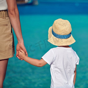 三岁的蹒跚学步的男孩在海滩上牵着妈妈的手。’暑假在马尔代夫度假。