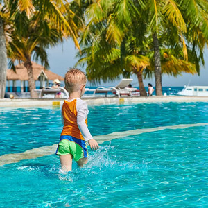 幼儿游泳摄影照片_三岁的蹒跚学步的男孩在度假村游泳池。暑假在马尔代夫度假。