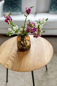 装饰和室内概念-玻璃花瓶中的龙花放在家里的圆形茶几上。家里茶几上的花瓶里的花