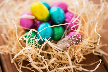 复活节，糖果和假日概念—巧克力蛋在稻草巢在木桌。巧克力复活节鸡蛋在稻草巢在桌子上