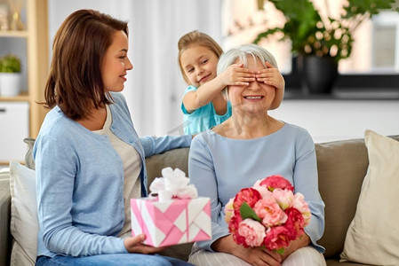 家庭，世代和生日—母亲和女儿在家里问候快乐的祖母。母亲和女儿在家里问候祖母