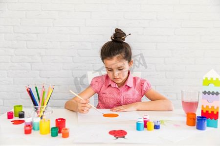 艺术家小朋友在白砖墙上画白纸桌