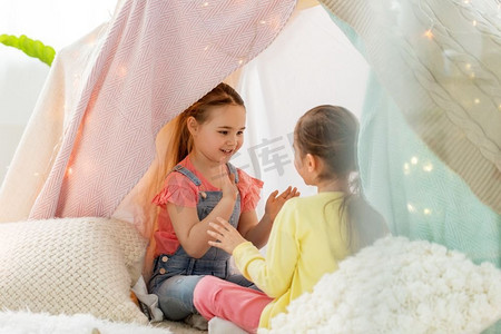 童年，hygge和友谊概念—愉快的女孩玩鼓掌游戏在孩子们帐篷在家里女孩玩鼓掌游戏在孩子们帐篷在家里