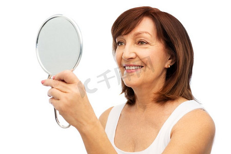 老年镜摄影照片_美丽和老人概念微笑的高级妇女肖像有镜子在白色背景肖像微笑的高级妇女与镜子