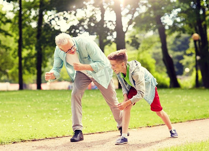 家庭、世代和人的概念-快乐的祖父和孙子在夏季公园赛车。祖父和孙子在夏季公园赛车