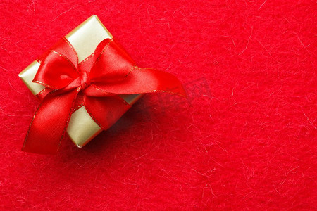 周年福礼摄影照片_节日，礼物，圣诞节的概念。小的金色盒子与礼品系在红色背景装饰弓与复制空间
