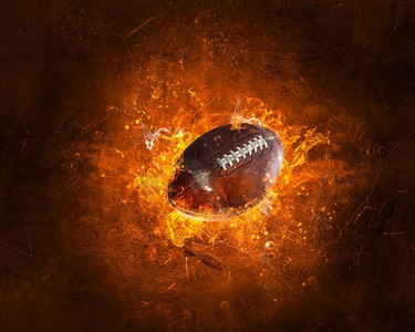 橄榄球在黑暗的背景下燃烧起来。混合媒体。美式足球比赛的概念。混合介质
