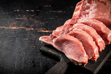 红色照片背景摄影照片_生猪肉放在砧板上。在黑暗的背景下。高质量的照片。生猪肉放在砧板上。 