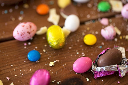 复活节，糖果和糖果概念—关闭的巧克力蛋和糖果滴在木桌。巧克力蛋和糖果滴在木桌上