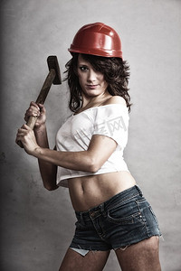 性别平等和女权主义。性感女孩戴着安全帽拿着锤子工具。做建筑工人的漂亮女人。