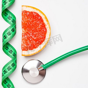 饮食健康饮食体重控制概念。葡萄柚与卷尺和听诊器的白色鳞片