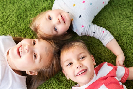 童年，休闲和家庭概念—快乐的小孩子躺在地板或地毯上。快乐的小孩子躺在地板或地毯上