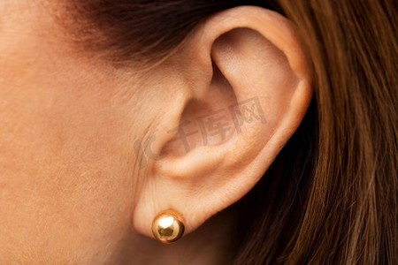健康、人与听觉概念—老年妇女戴金色耳环特写。关闭高级妇女耳朵与金色耳环