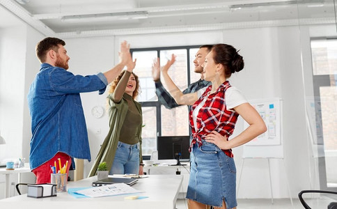商业、团队合作和企业理念—快乐的创意团队在办公室击掌。快乐的创意团队在办公室击掌