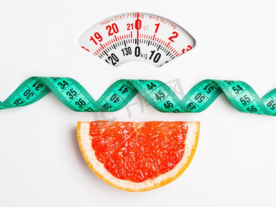 节食健康饮食瘦身理念。特写葡萄柚片，白磅秤上有卷尺