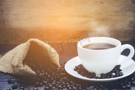 咖啡杯侧面视图与烟和咖啡豆在麻袋在木桌，饮料和放松概念，广告