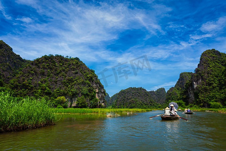 游客在越南宁平附近受欢迎的旅游目的地Tam Coc-Bich Dong Ngo East河上乘船。越南游客乘船游览