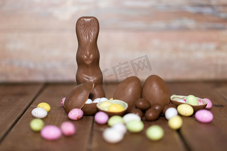 复活节，糖果和糖果概念—巧克力蛋，兔子和糖果滴在木桌。巧克力蛋，复活节兔子和木头糖果