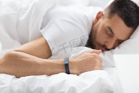 人，技术和休息概念—近摄人与活动跟踪器睡在床上。关闭的男子睡觉与活动跟踪器