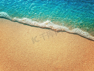 沙和水纹理背景。柔软的海水泡沫波浪在金色的沙滩上。