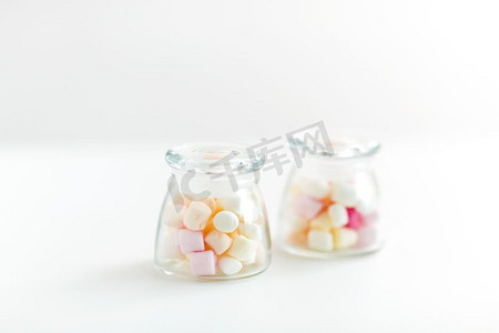 糖果罐摄影照片_食物，糖果和糖果概念—关闭罐与棉花糖在白色背景。关闭的罐子与棉花糖