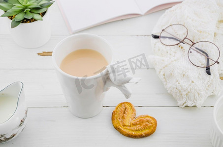 茶杯书摄影照片_palmiers象耳粉饼饼干与瓷白茶杯木桌子