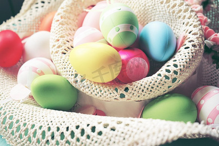 一个美丽的和丰富多彩的特写复活节彩蛋在平原粉彩的颜色和条纹在一个篮子与鲜花